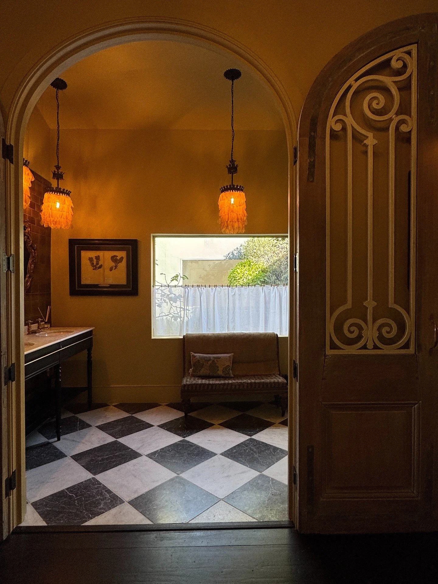 Ornate arched doorway opening into a tiled powder room