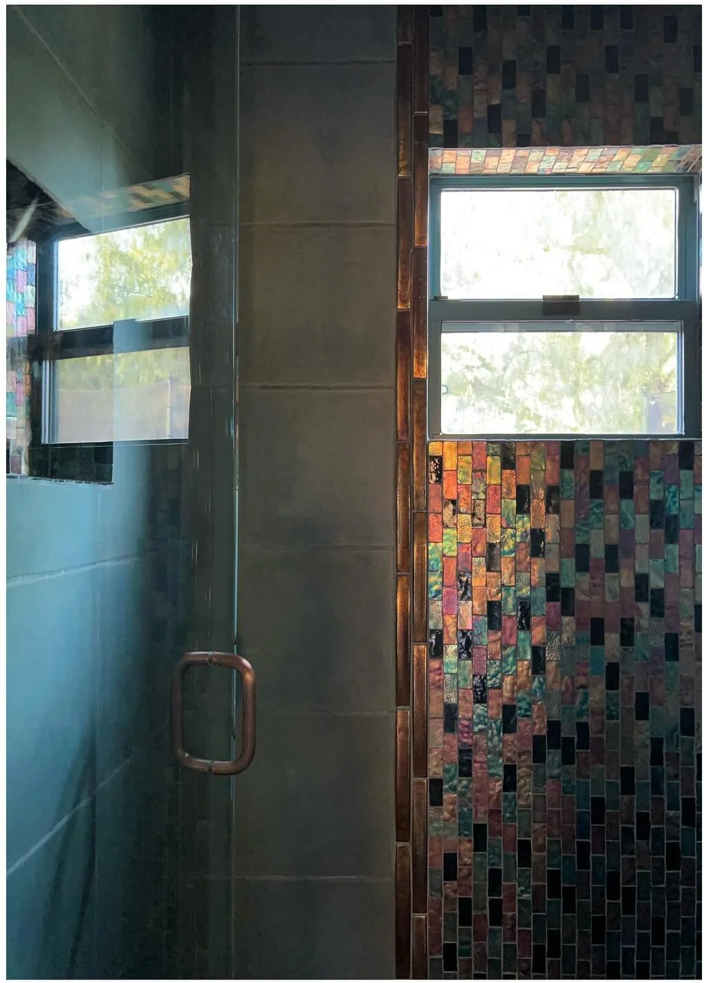 Shower window surrounded by colorful small mosaic tiles
