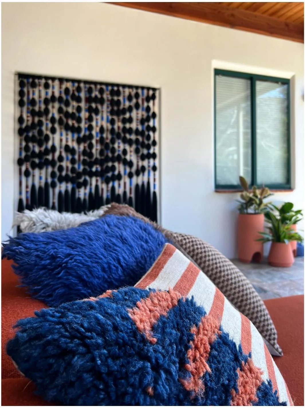 Blue and orange cushion beside a black-and-white textile wall hanging