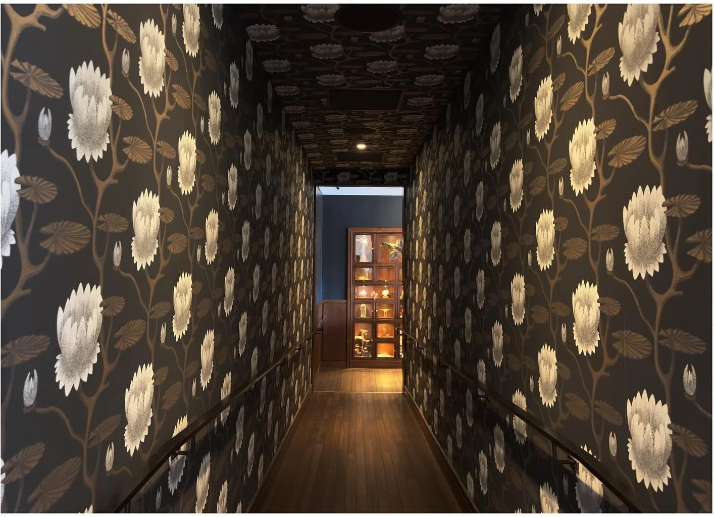 Floral wallpaper wrapping the walls and ceiling of a corridor