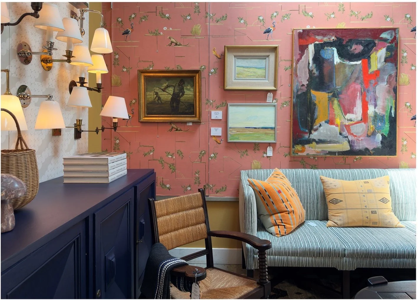 Pink showroom wall with framed art and a pale blue settee