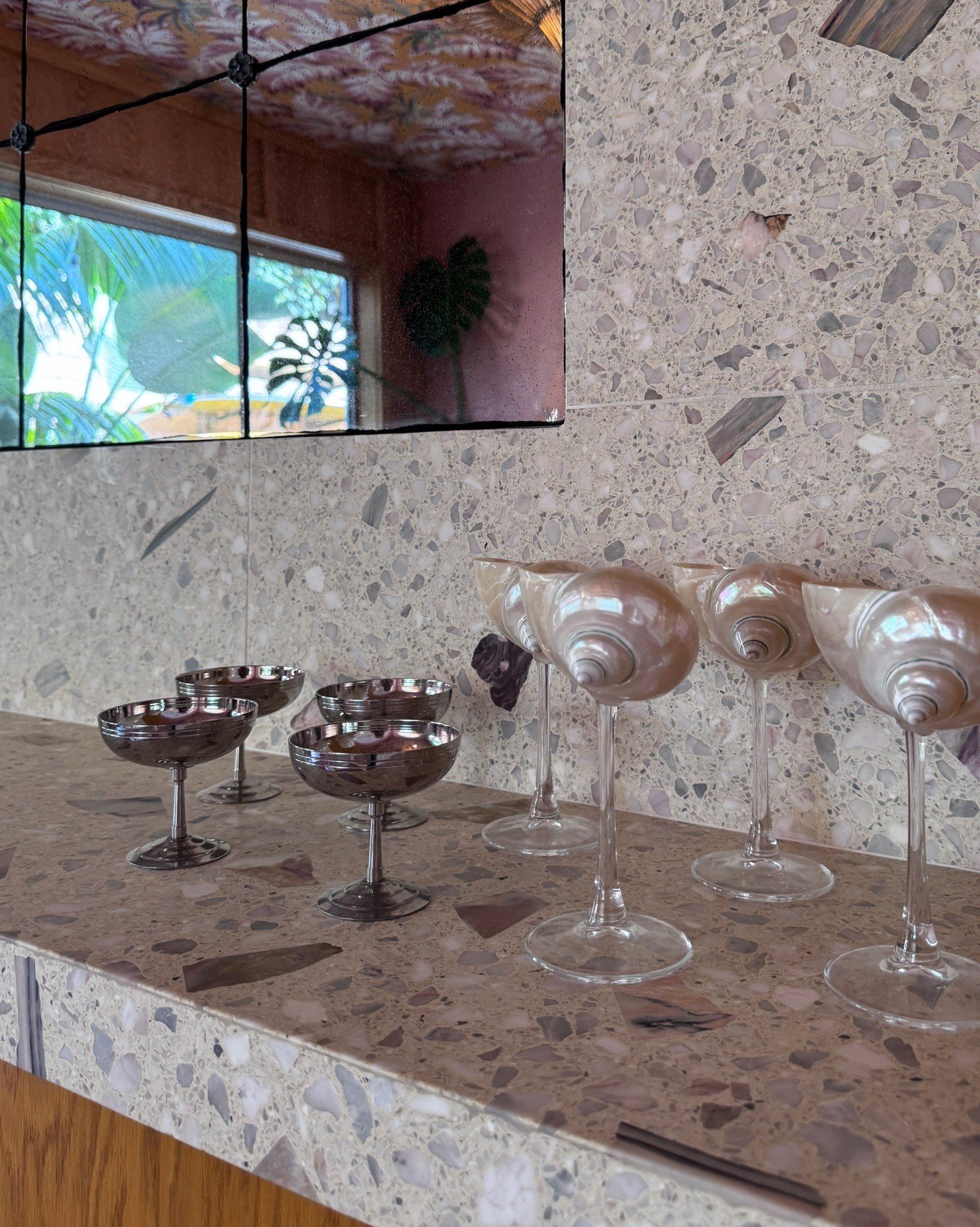 Wine glasses on a terrazzo countertop beneath a small window