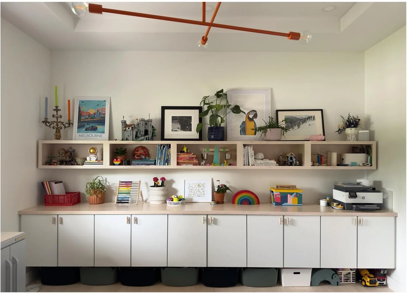 White cabinets and open shelves displaying books art and toys