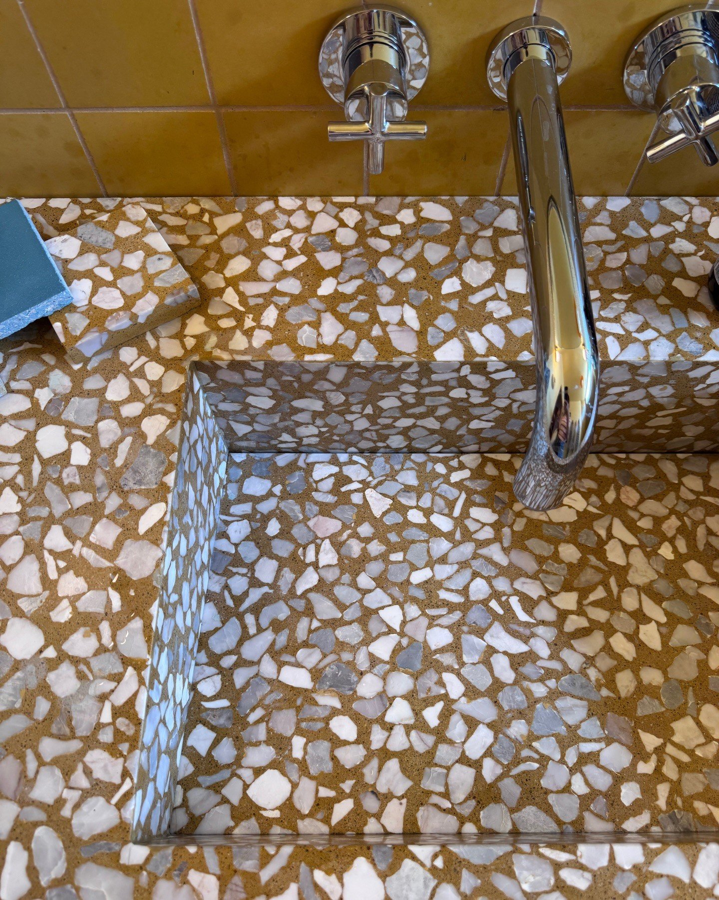Close-up of yellow terrazzo sink with a chrome faucet
