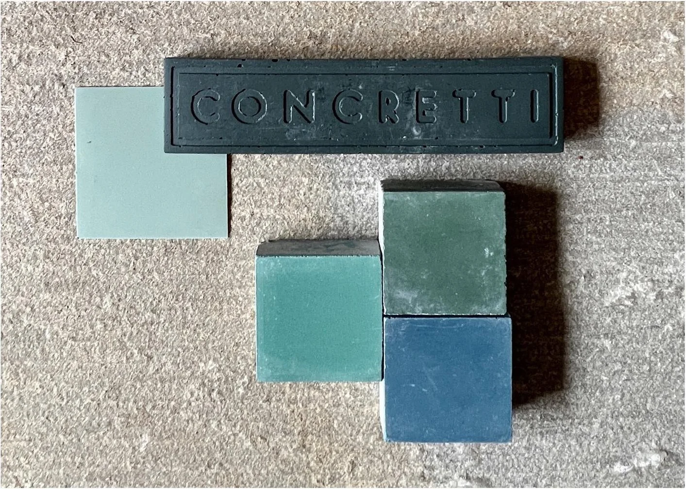 Deep green concrete sample with blue and teal tile chips
