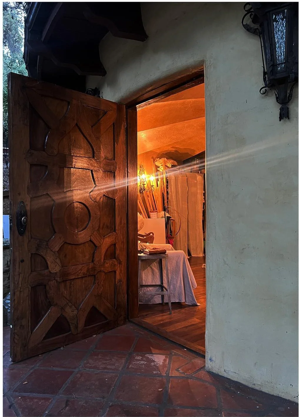 Open carved wood door leading into a warmly lit studio