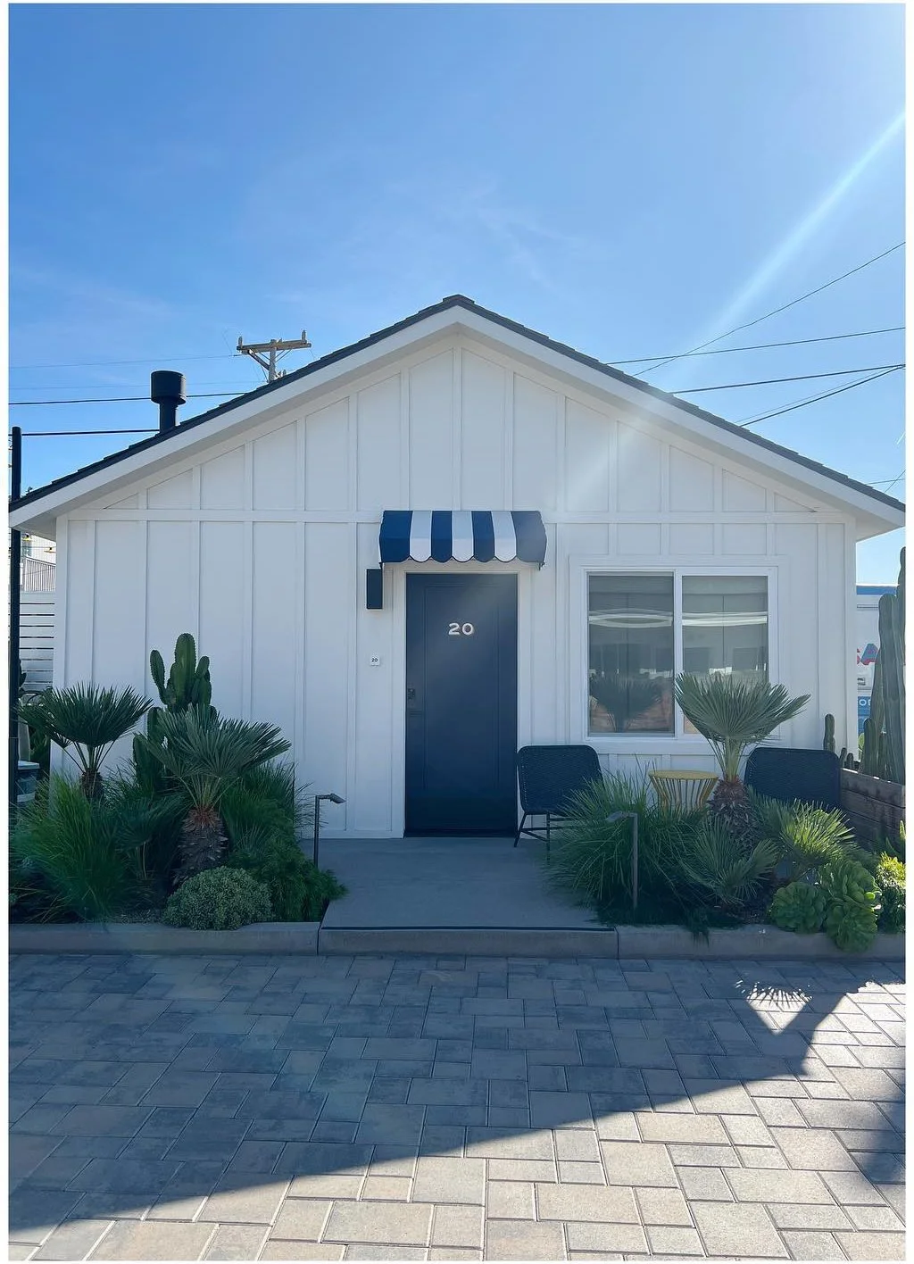 White motel cottage with blue door and low garden planting