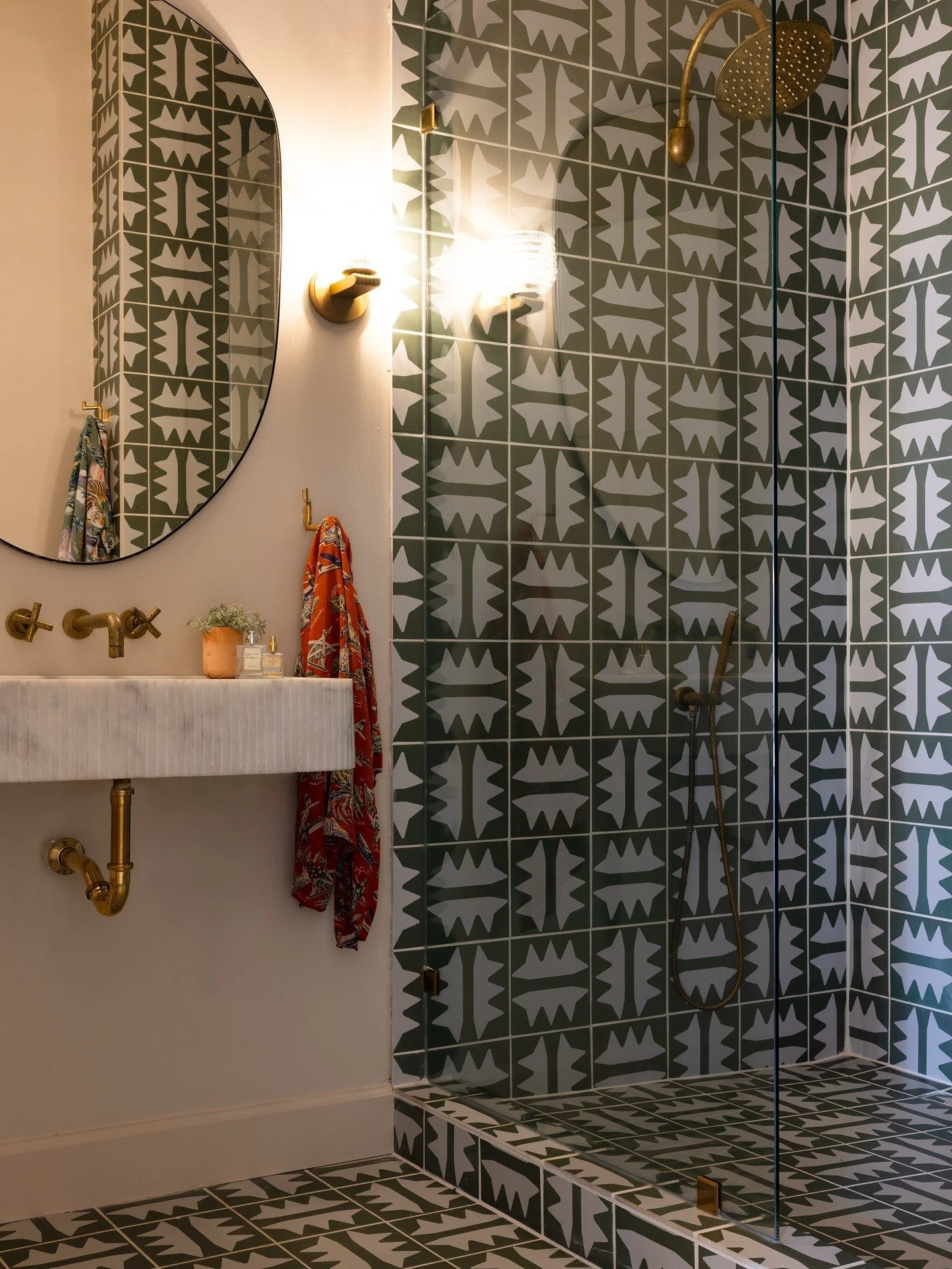 Compact bathroom wrapped in olive and cream patterned tile