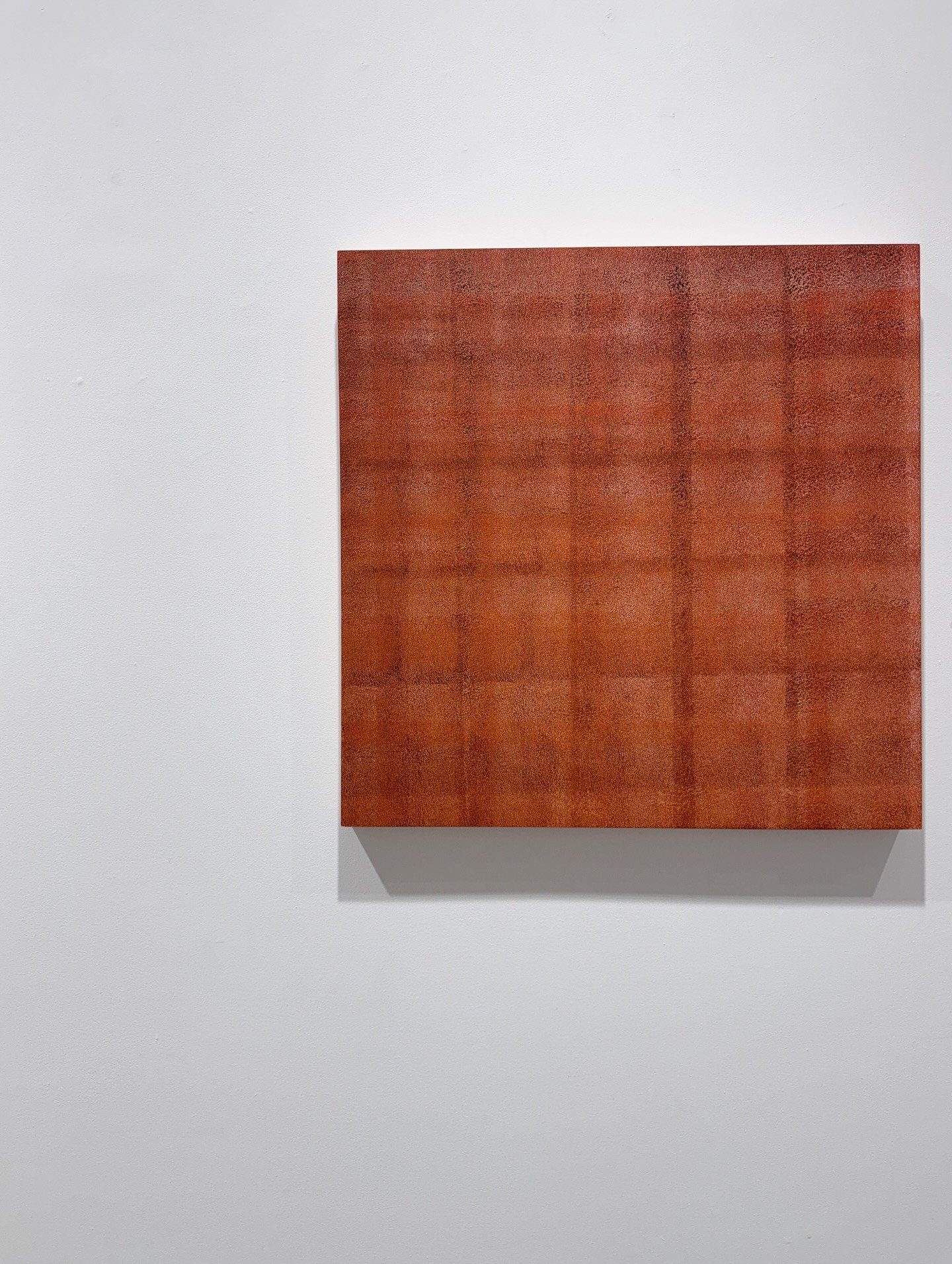 Orange abstract square painting mounted on a white wall