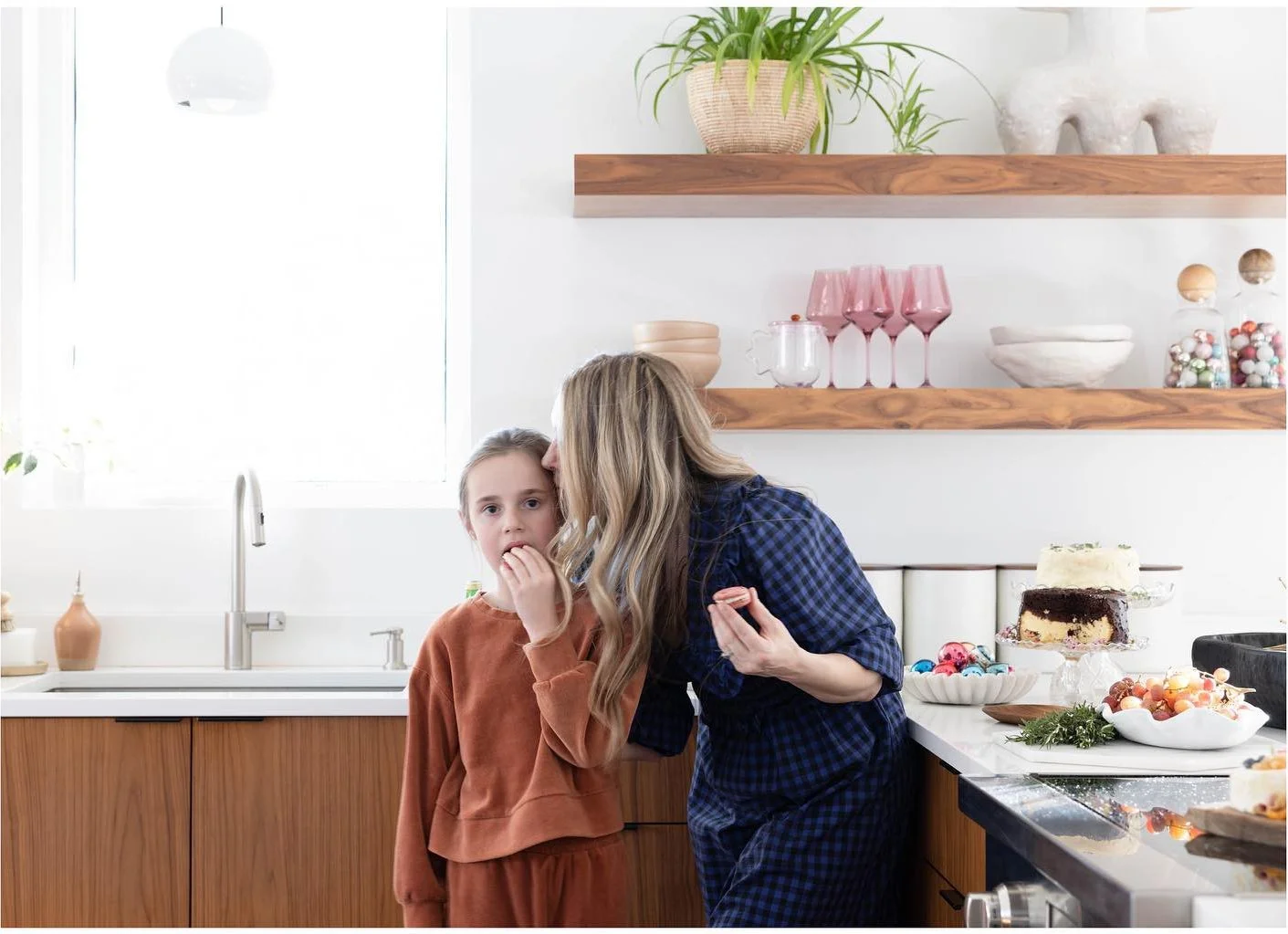 Two members of the styling team talking beside wood kitchen shelves