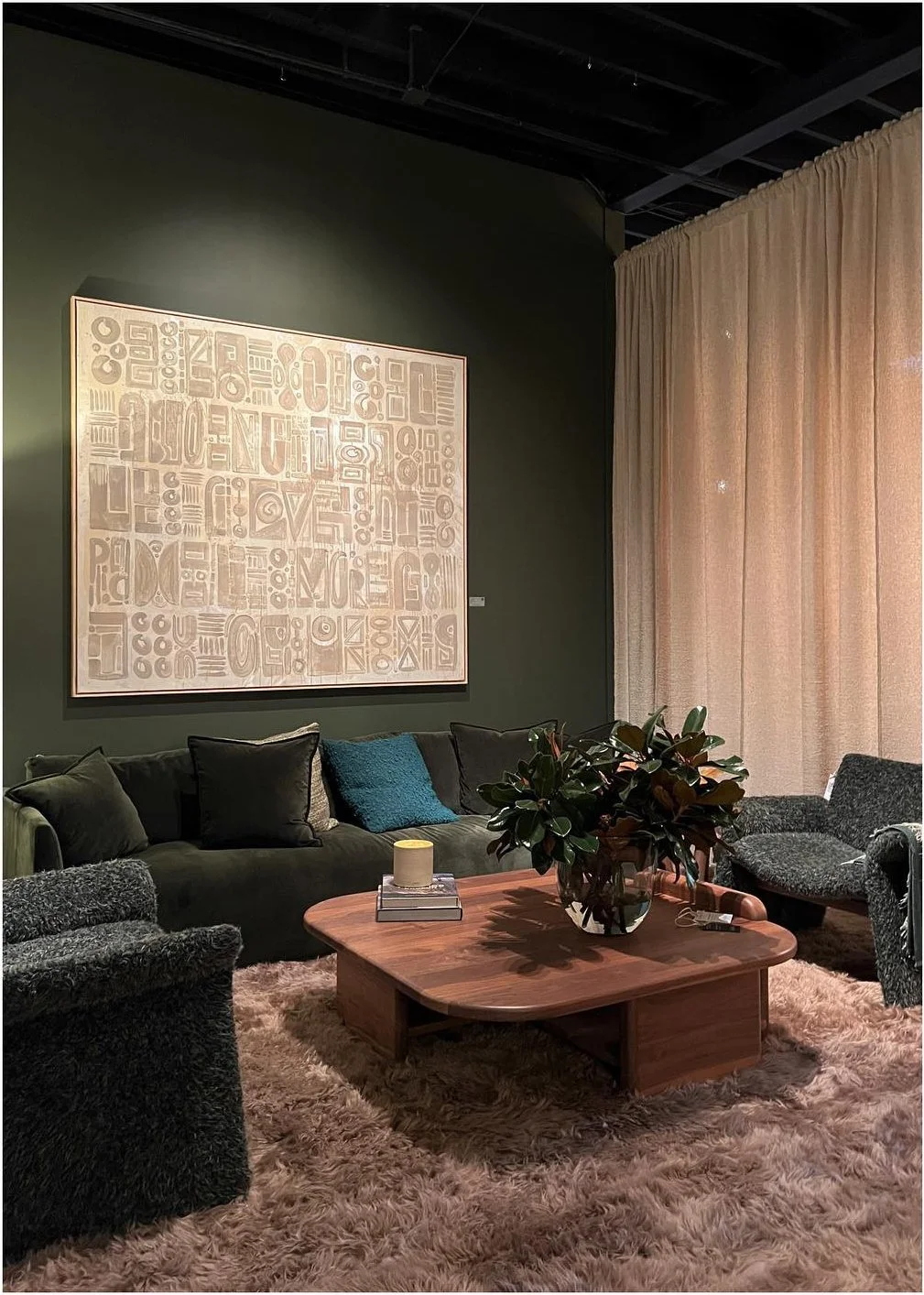 Moody showroom sitting area with dark upholstery and a sculptural wood coffee table