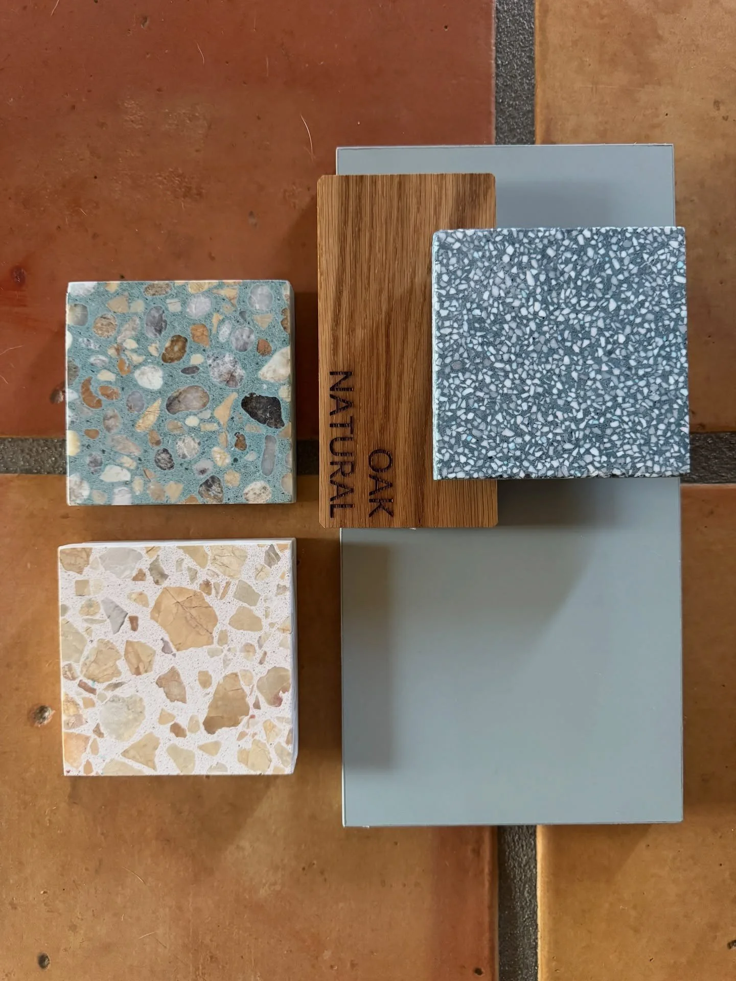 Blue-gray tile wood and terrazzo samples on terracotta flooring