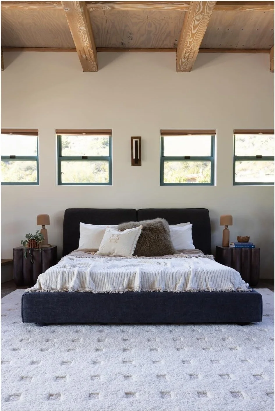 Low upholstered bed centered on a large pale wool rug
