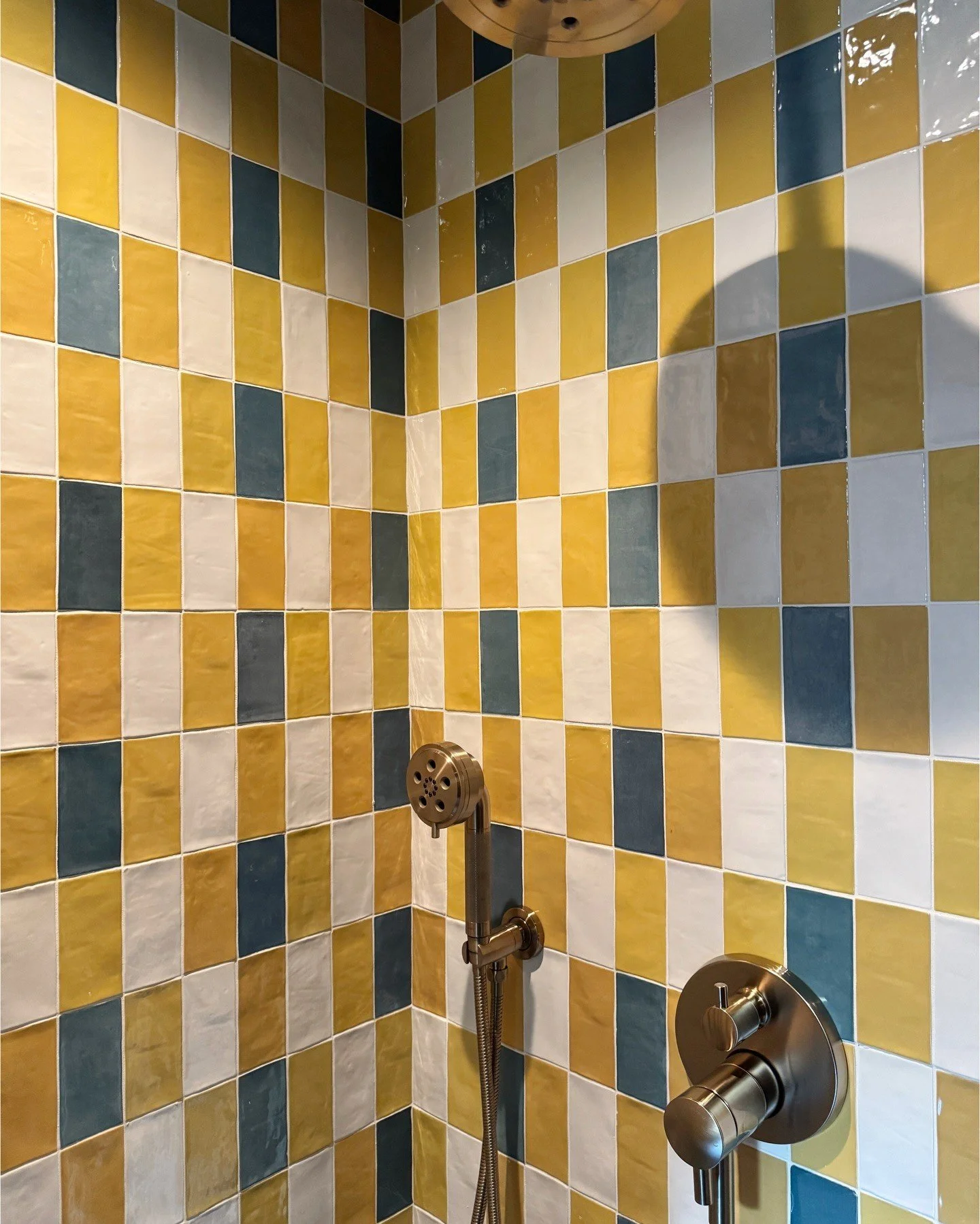 Yellow and gray checkerboard tile shower with chrome fittings