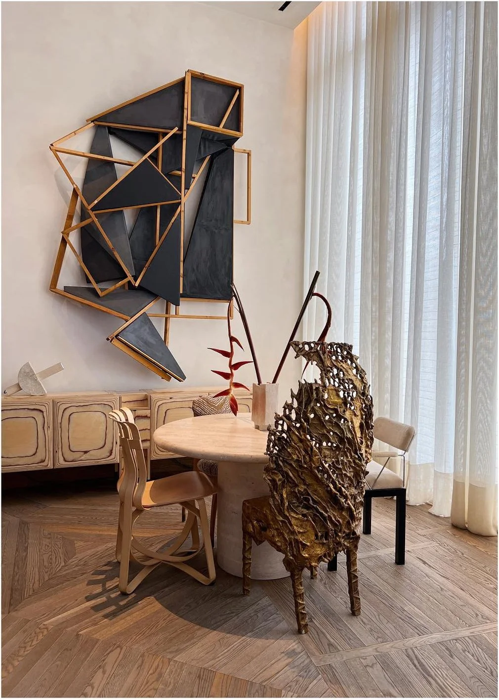 Designer seated at a pale table beneath geometric wall art