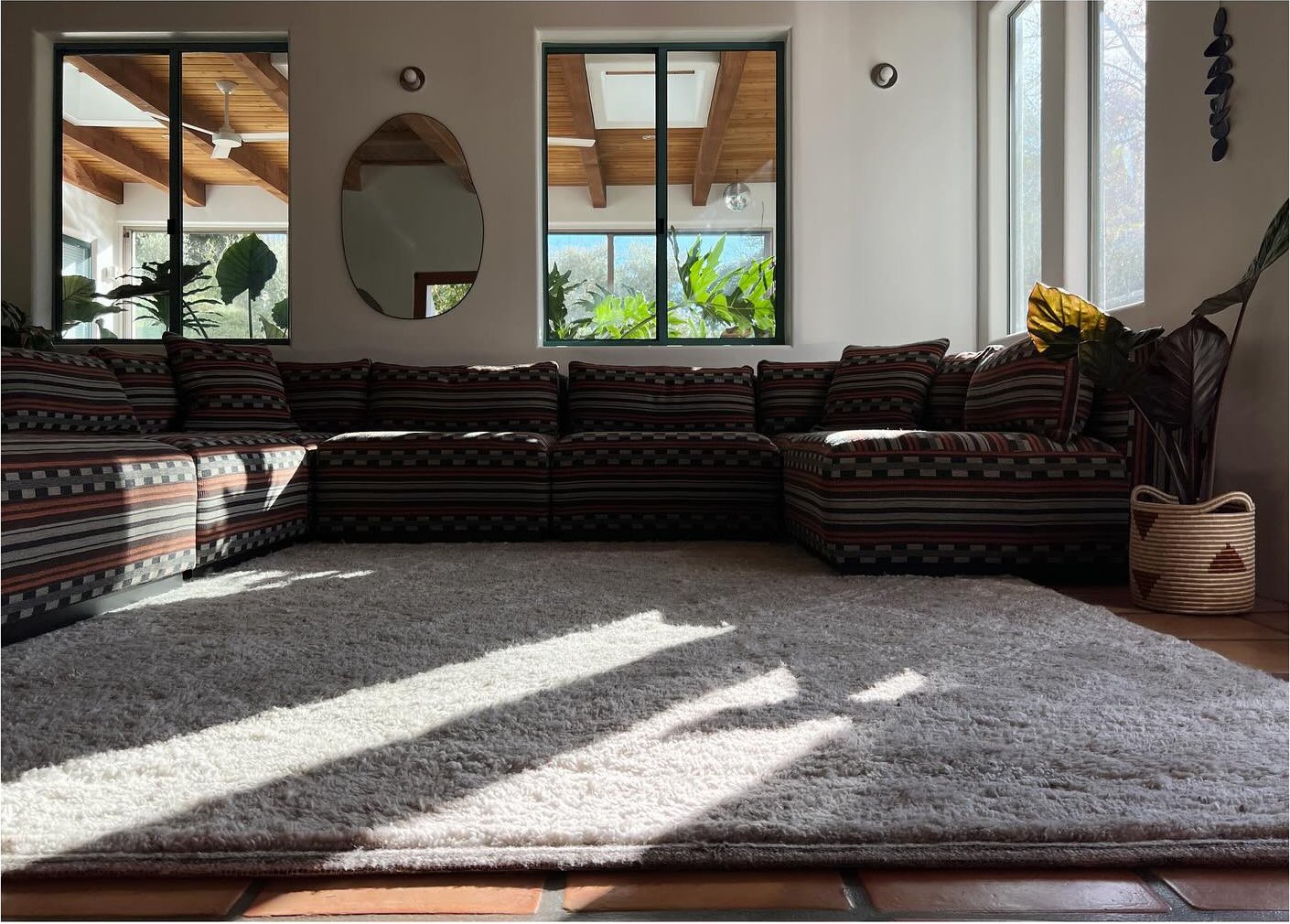 Sunlight across a large pale rug in a timber-beamed living room