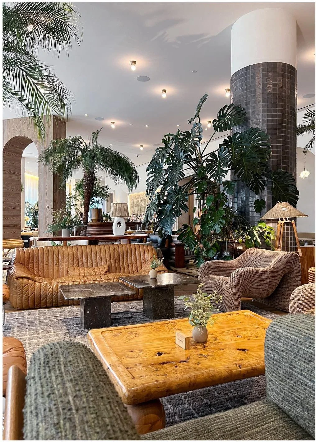 Hotel lounge with sculptural stone tables plants and warm wood details