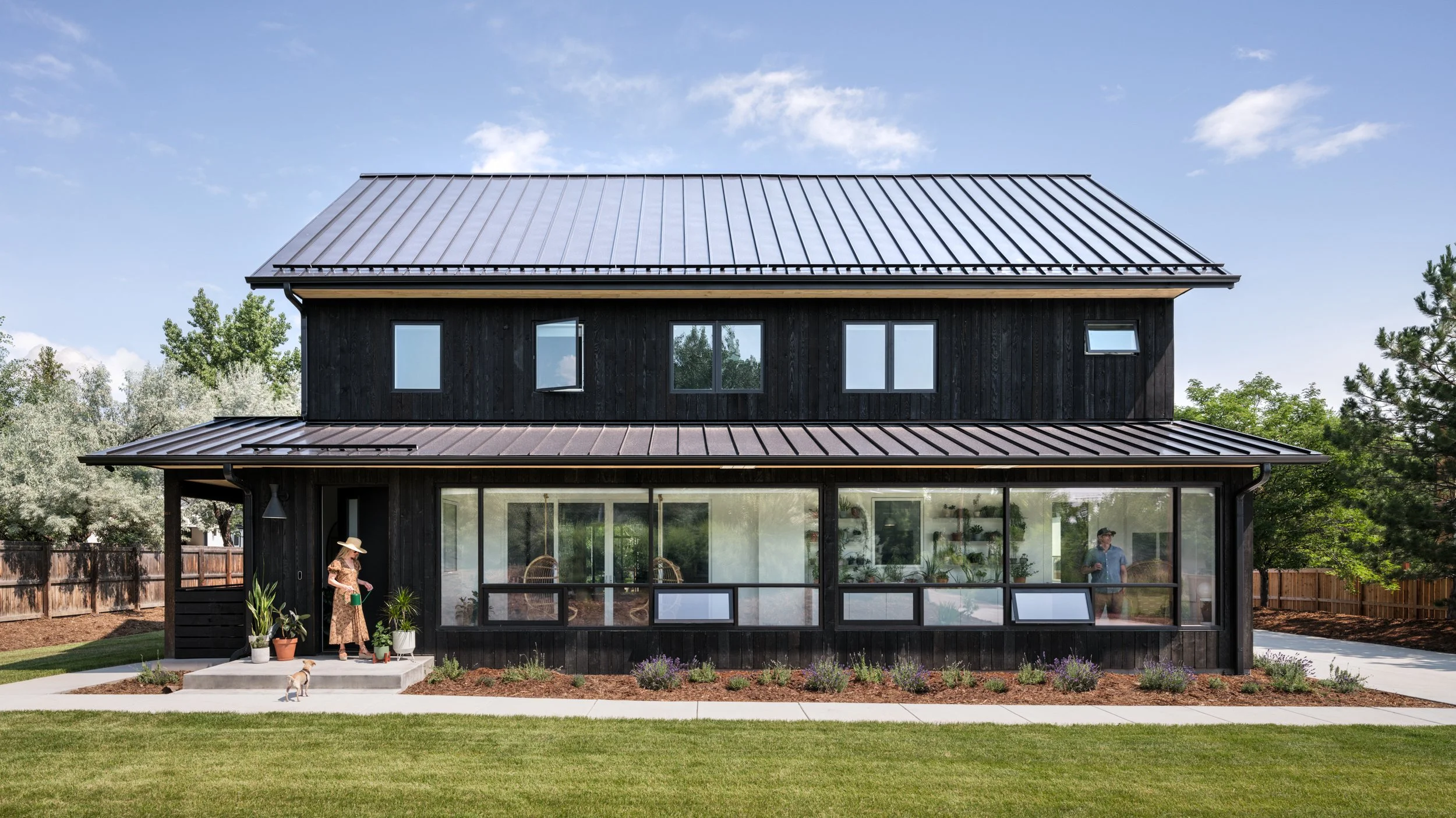 Exterior of a dark wood home with a covered patio and lawn.