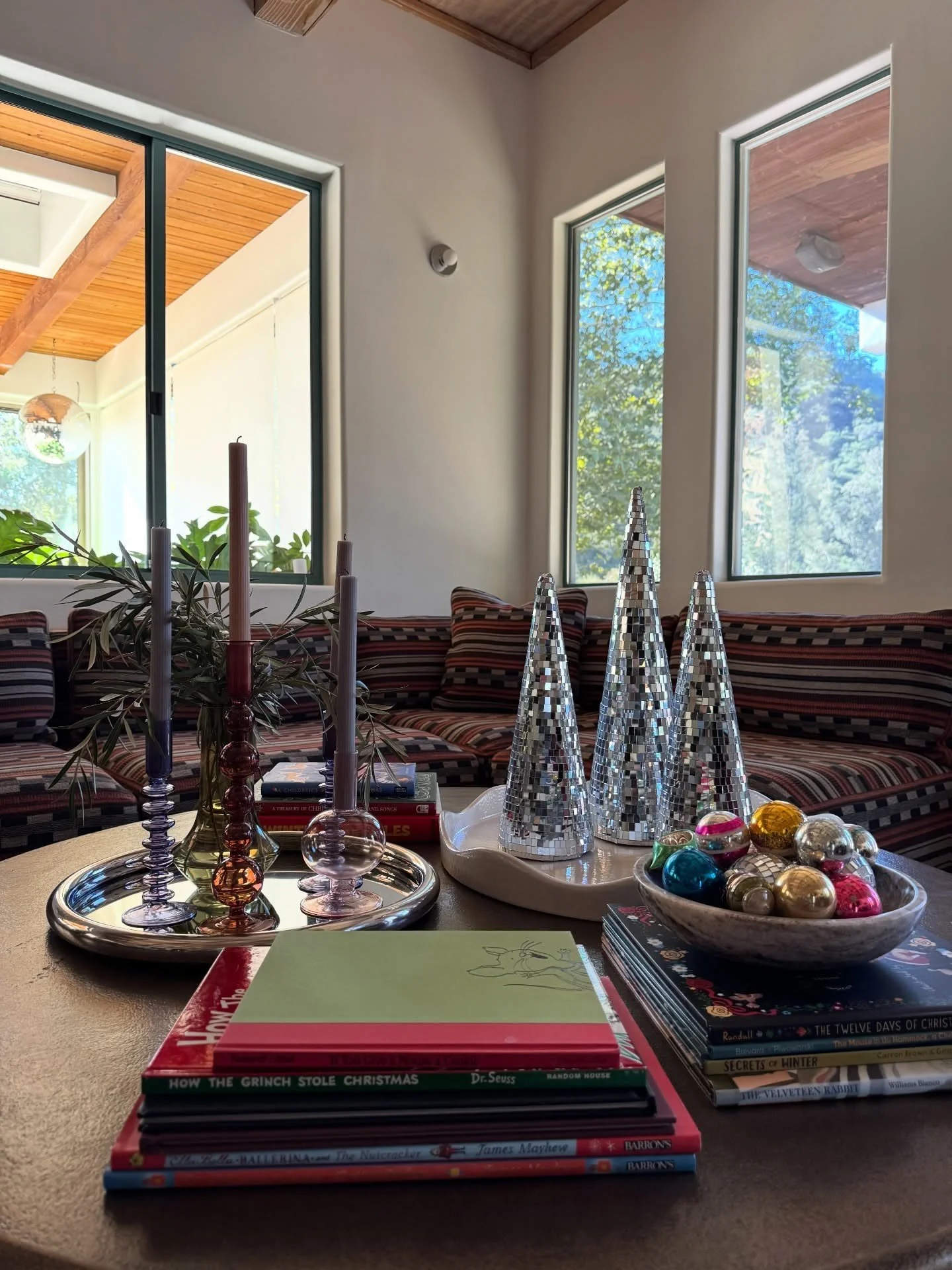 Holiday coffee table styling beside sunlit windows and patterned seating