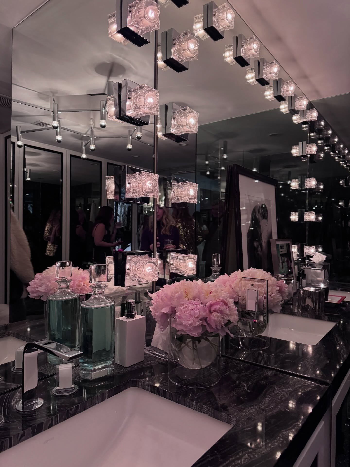 Mirrored bathroom with pink flowers and crystal wall lighting