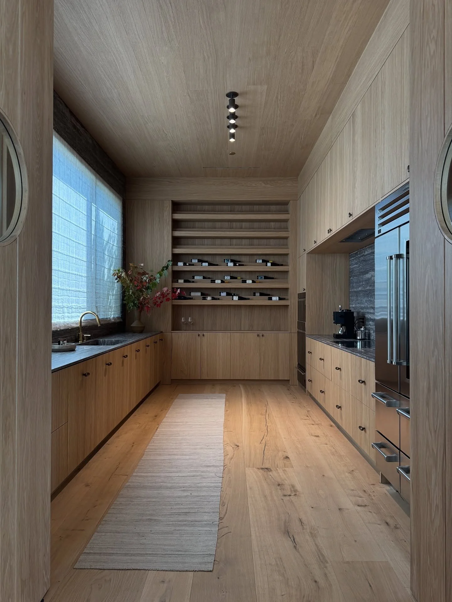 Wood kitchen cupboards and shelves beneath a pitched ceiling