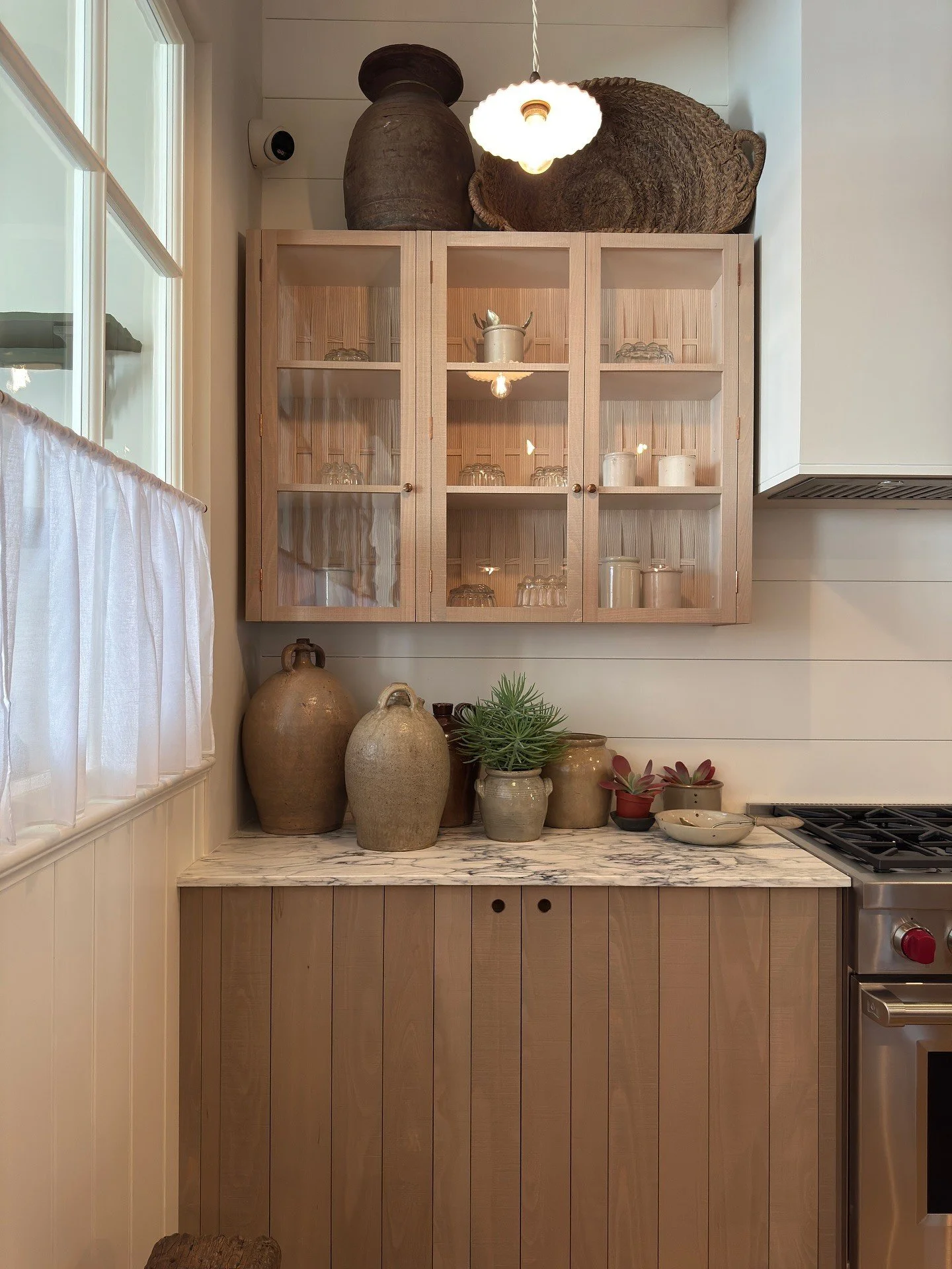 Glass-front wood cabinet above a pale stone counter