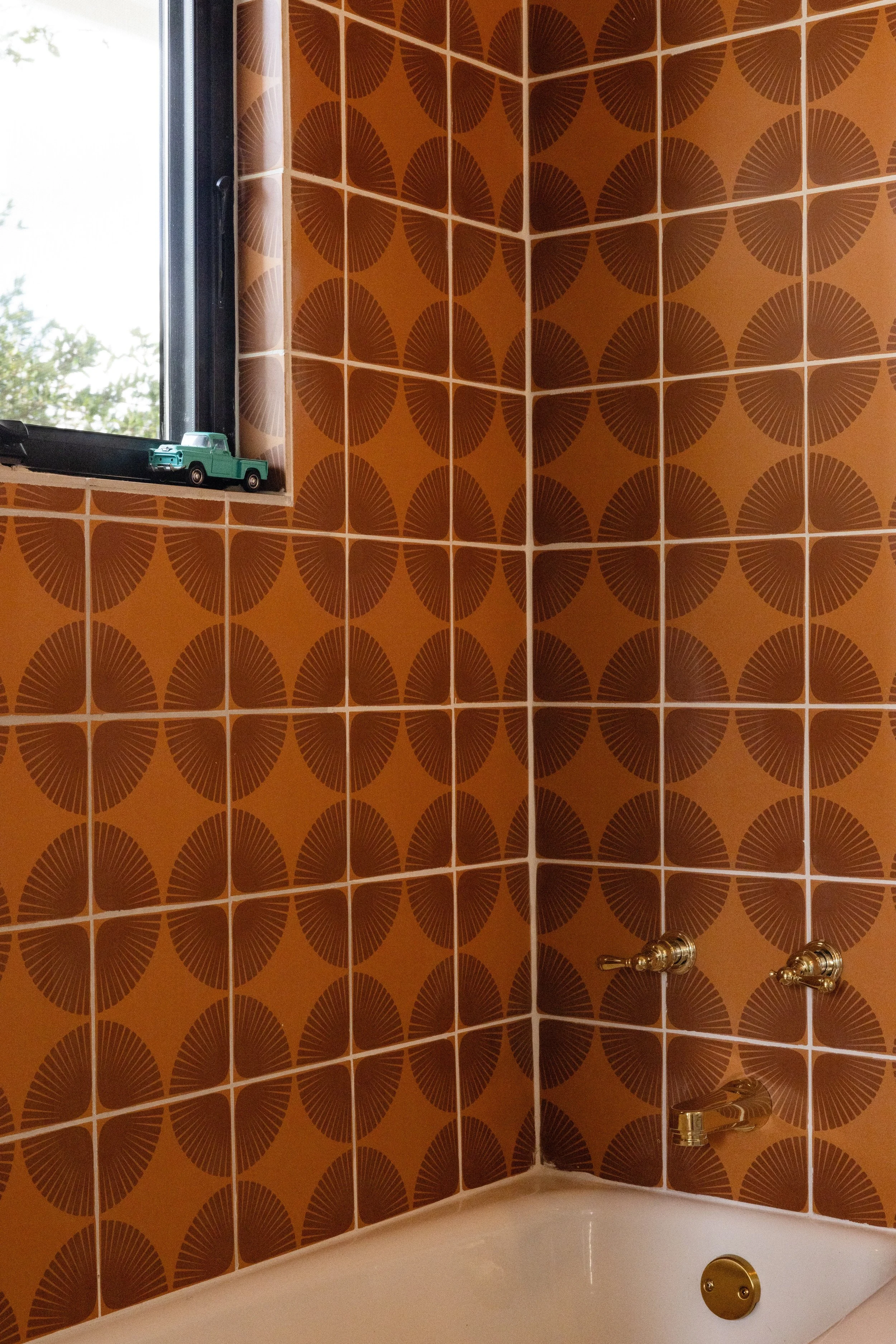 Bathtub surrounded by warm orange geometric tile.