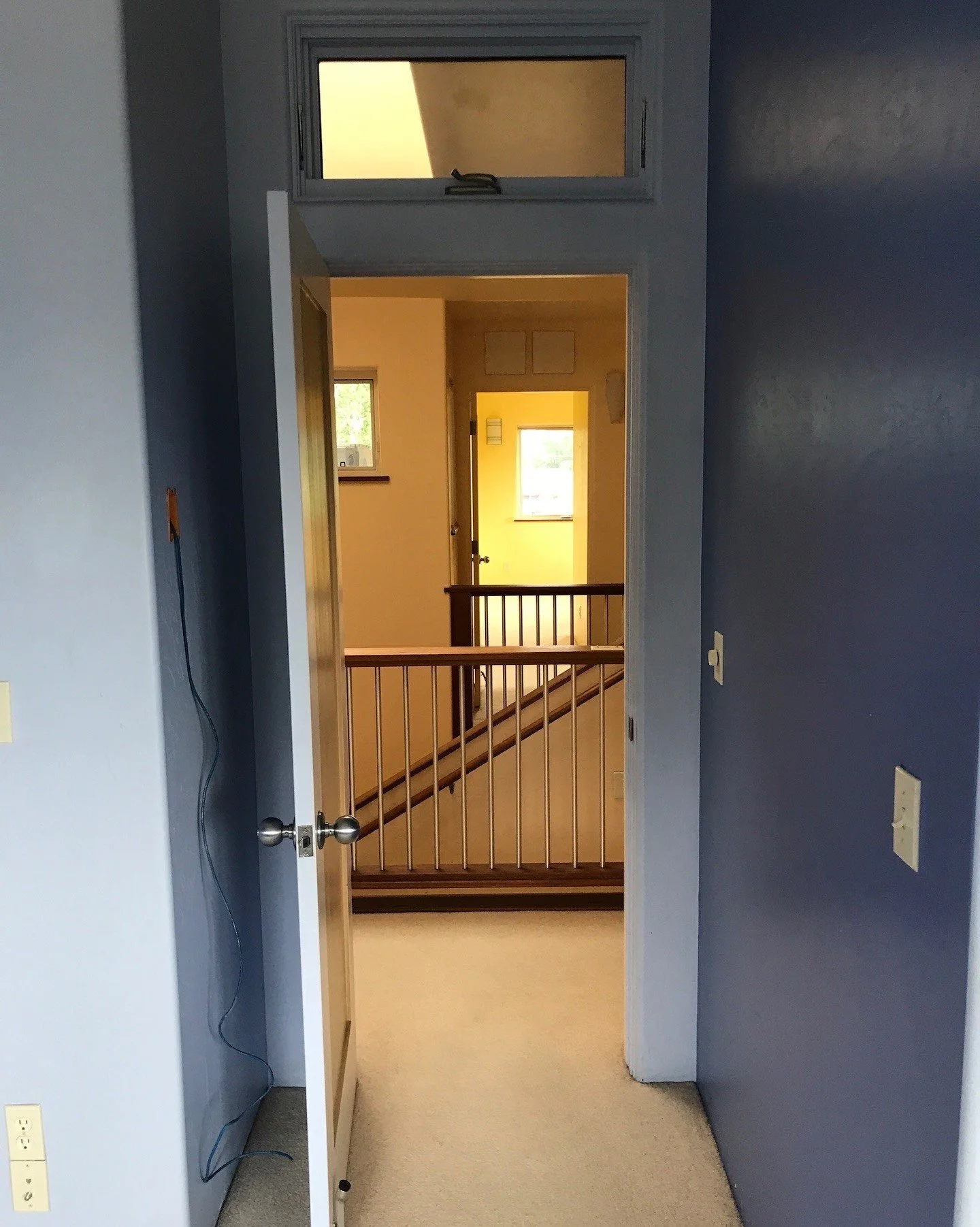 Dark hallway opening toward a yellow room before renovation