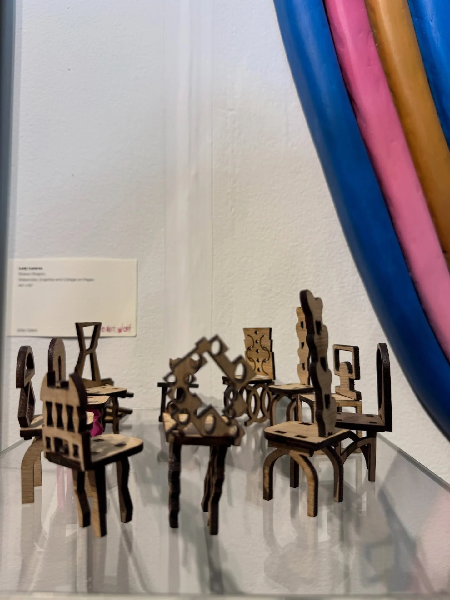 Sculptural carved chairs arranged beneath colorful wall graphics