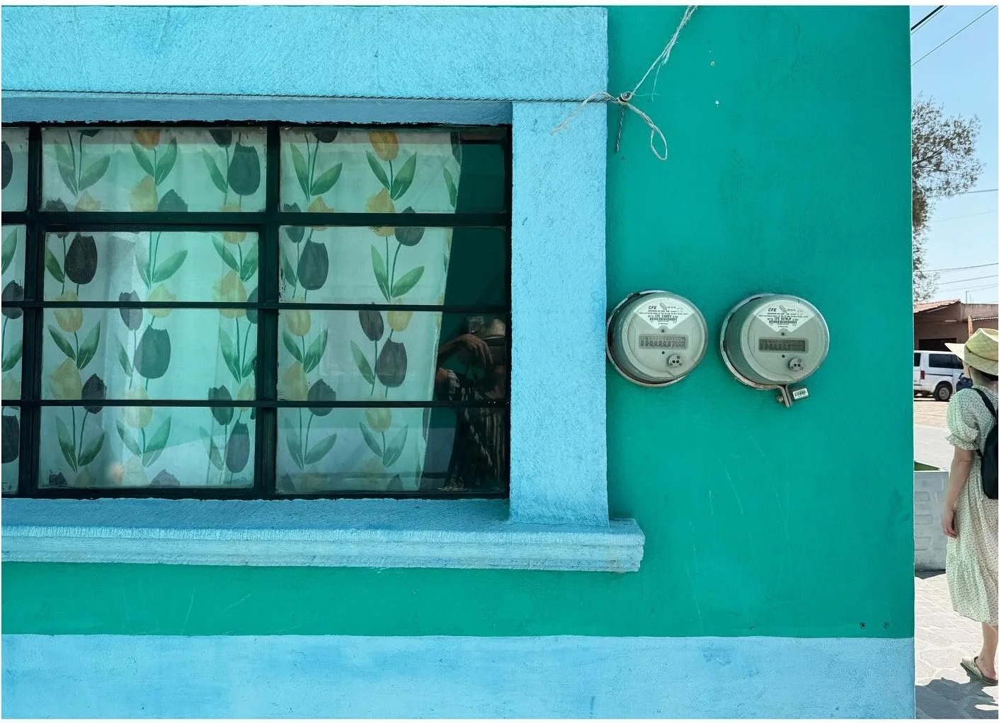 Turquoise facade with a blue window frame and patterned curtains