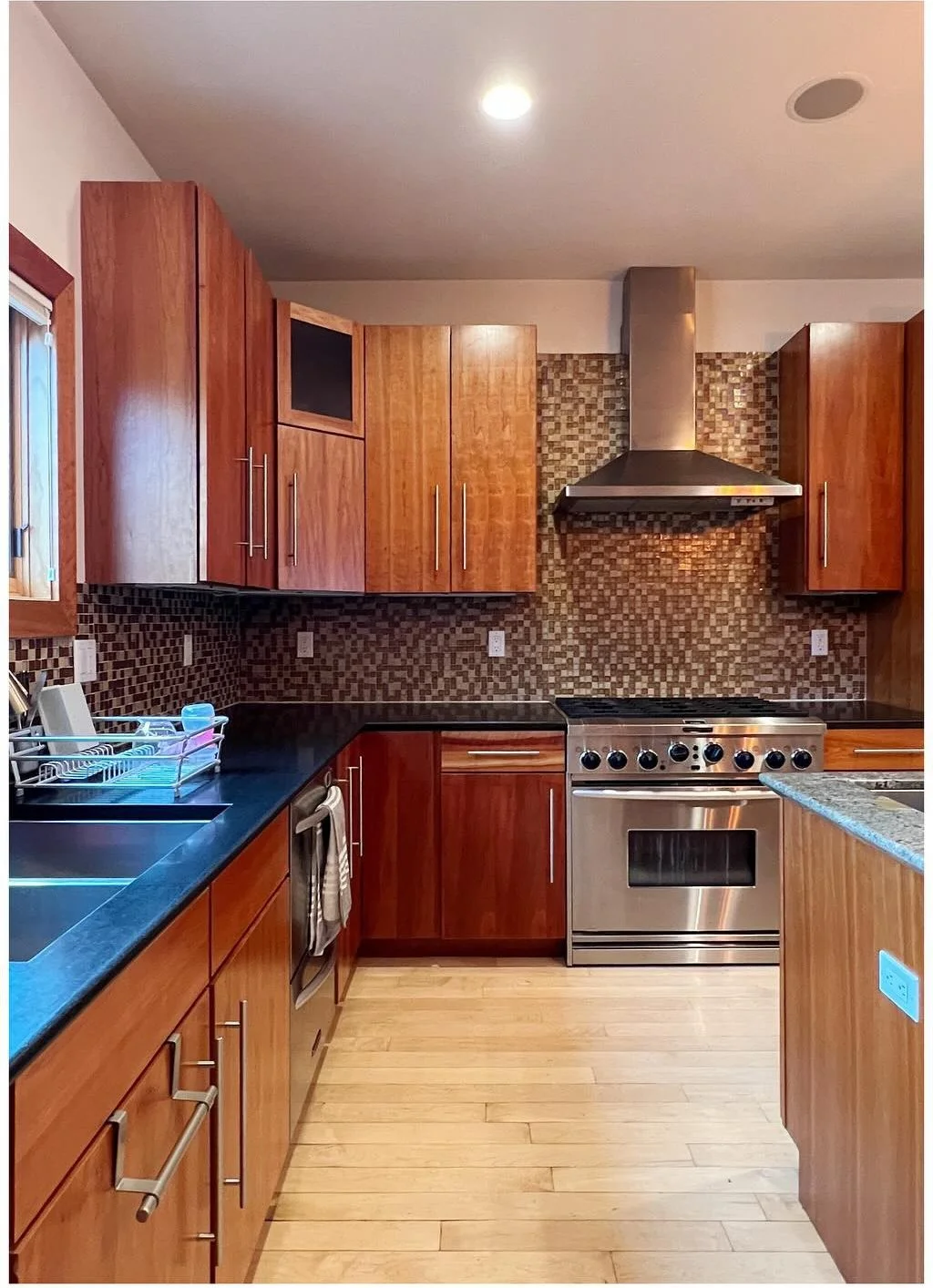 Original stove wall with wood cabinetry and mosaic tile backsplash