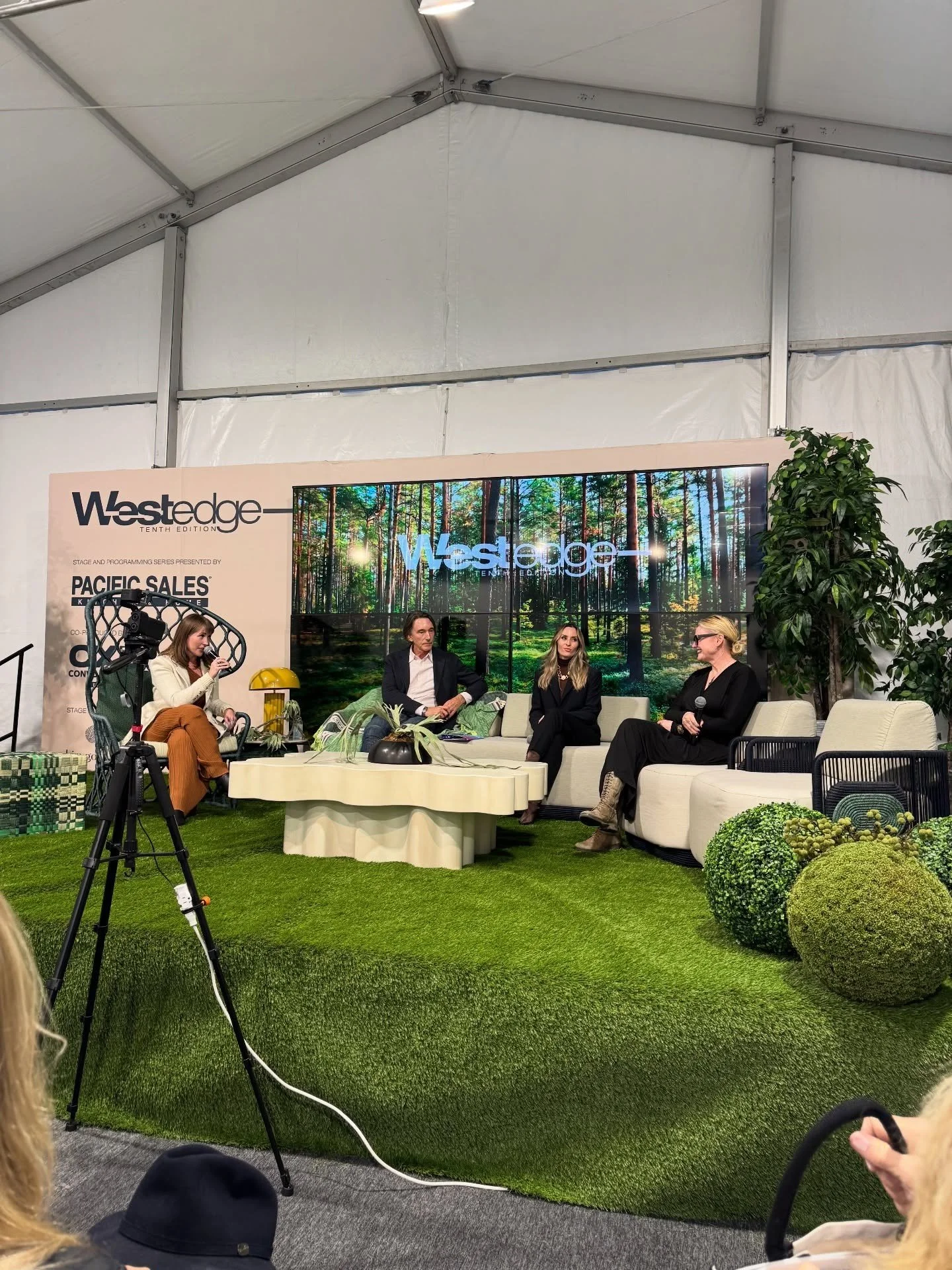 Outdoor design panel seated on pale furniture beside planting