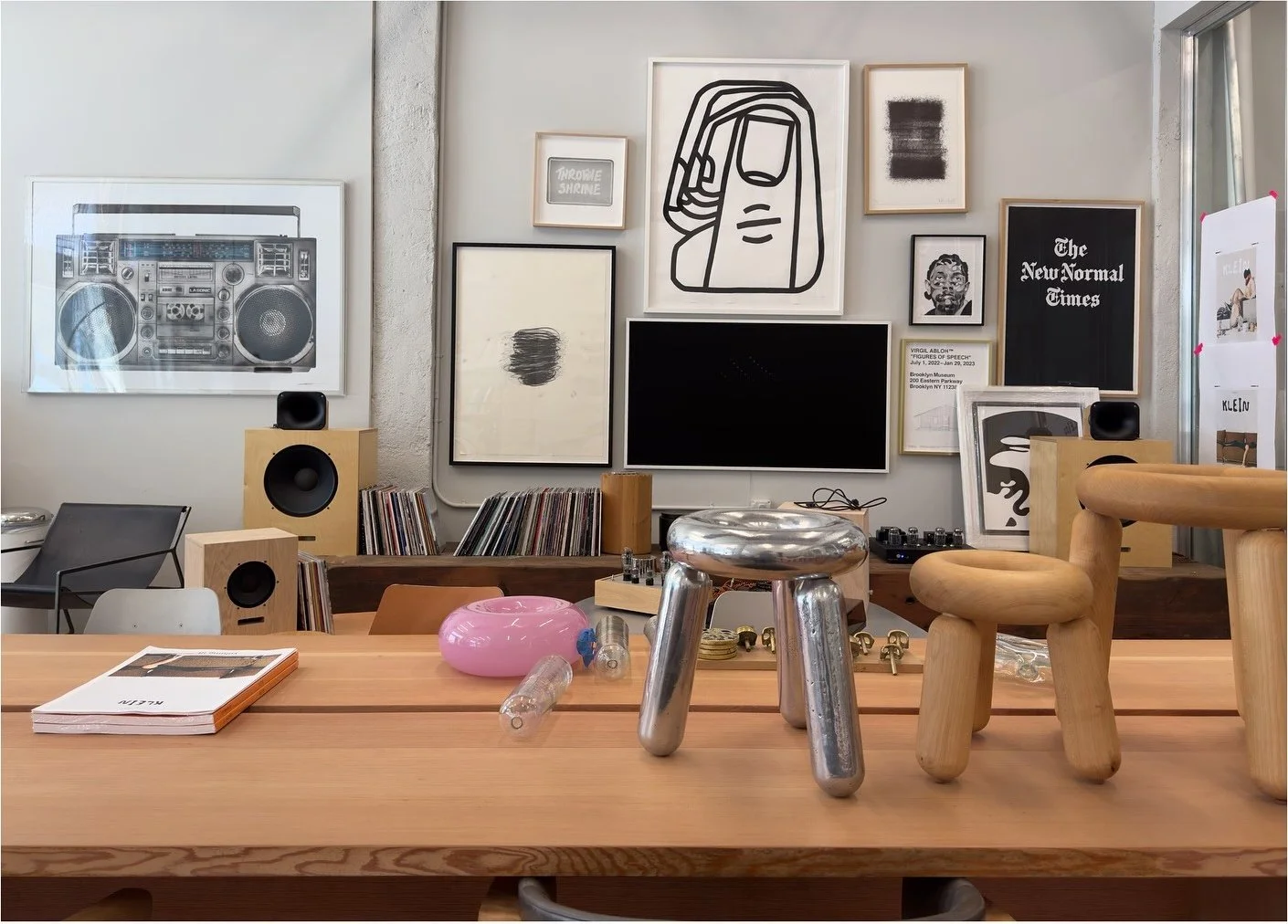 Studio worktable with small objects beneath a gallery wall
