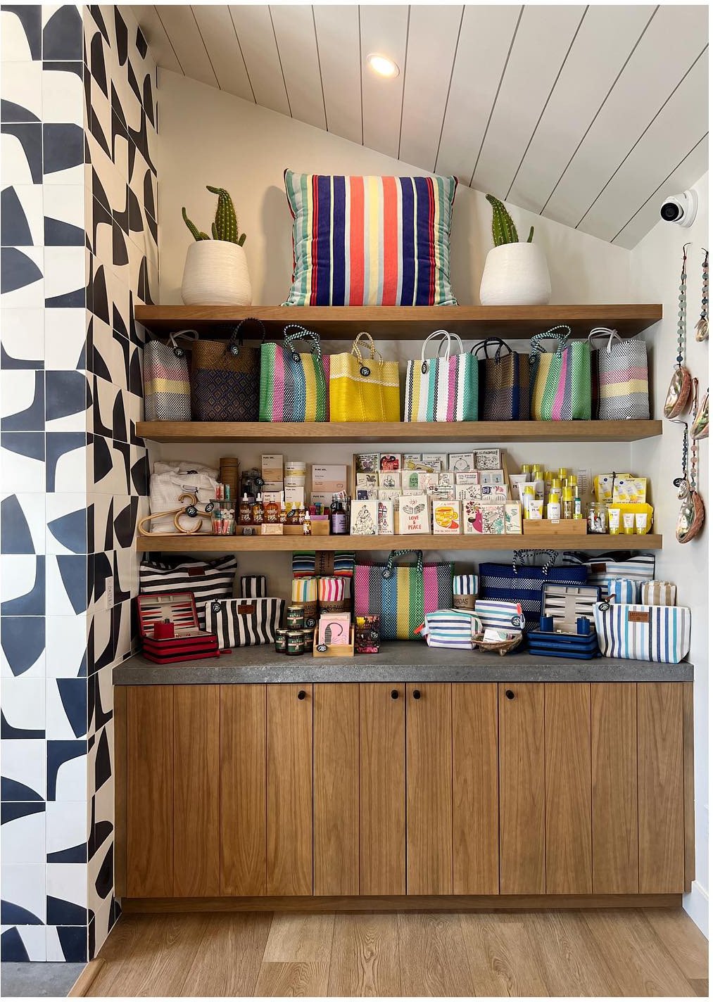 Wood cabinet and open bookshelves against graphic black-and-white wallpaper