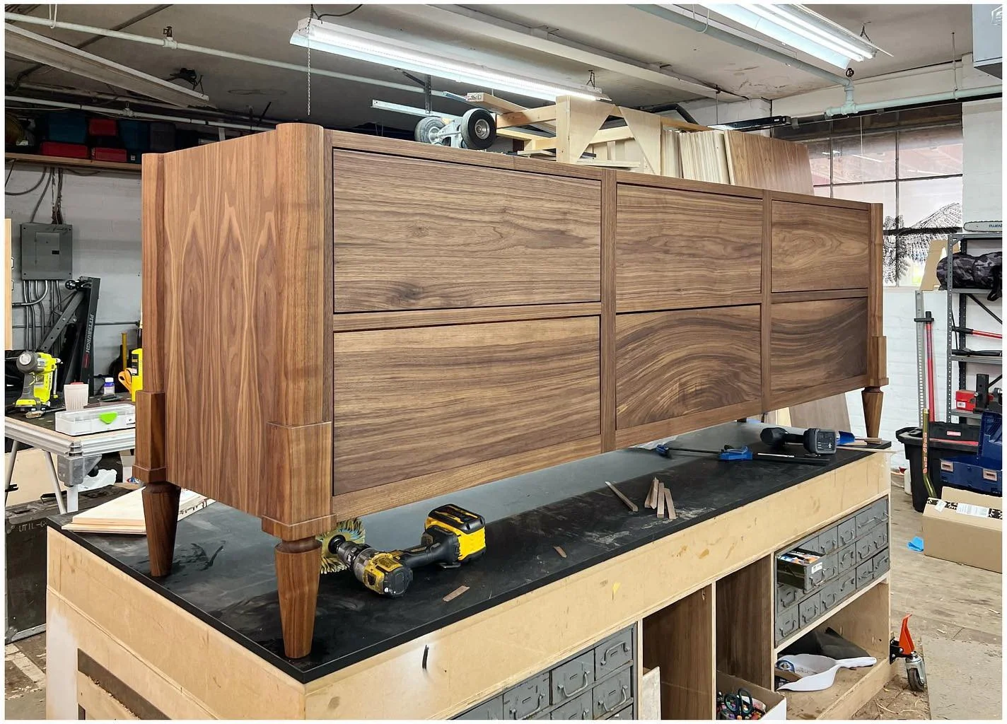 Long walnut vanity cabinet under construction on a workshop bench