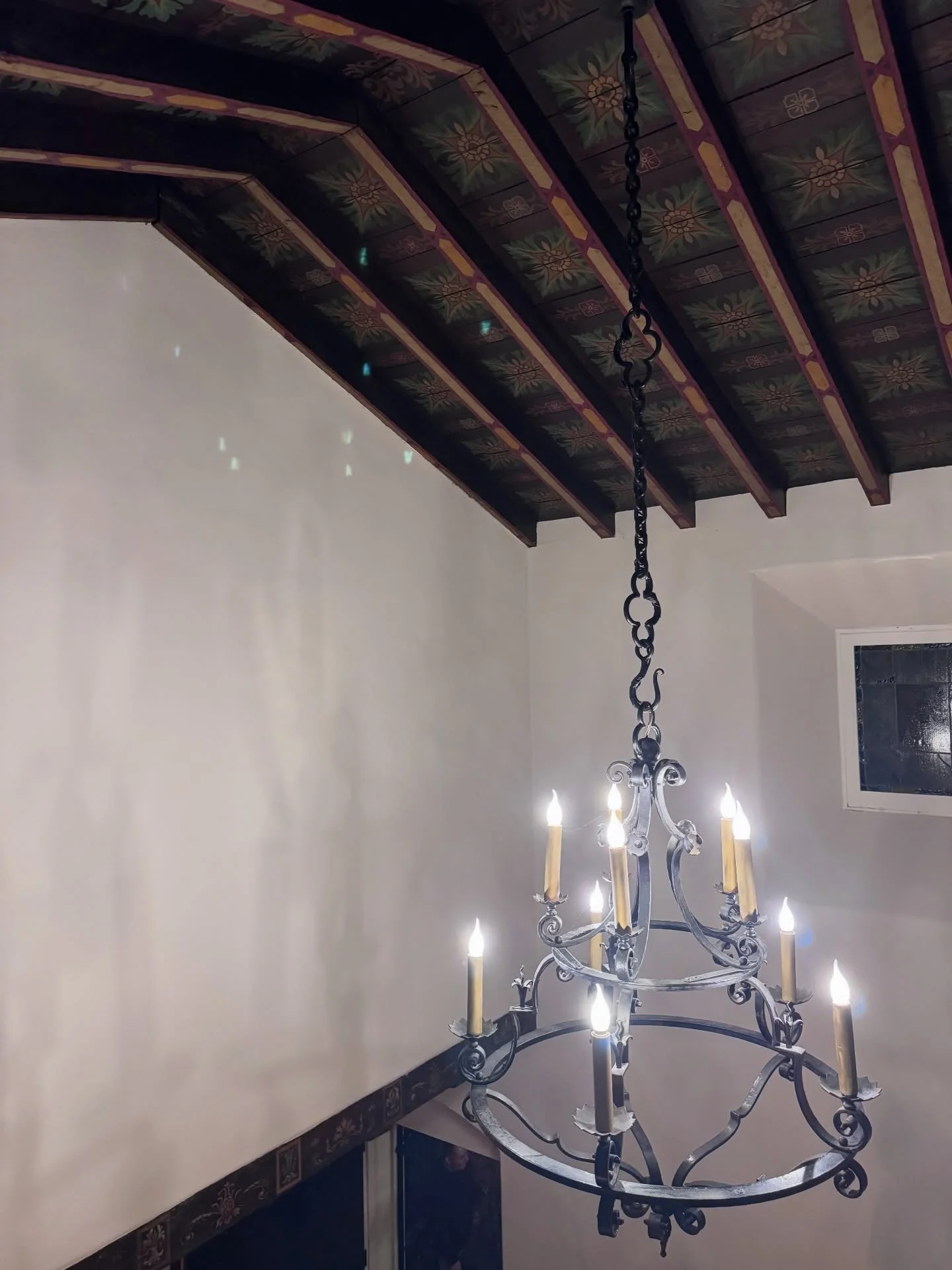 Wood ceiling beams above a hanging metal chandelier