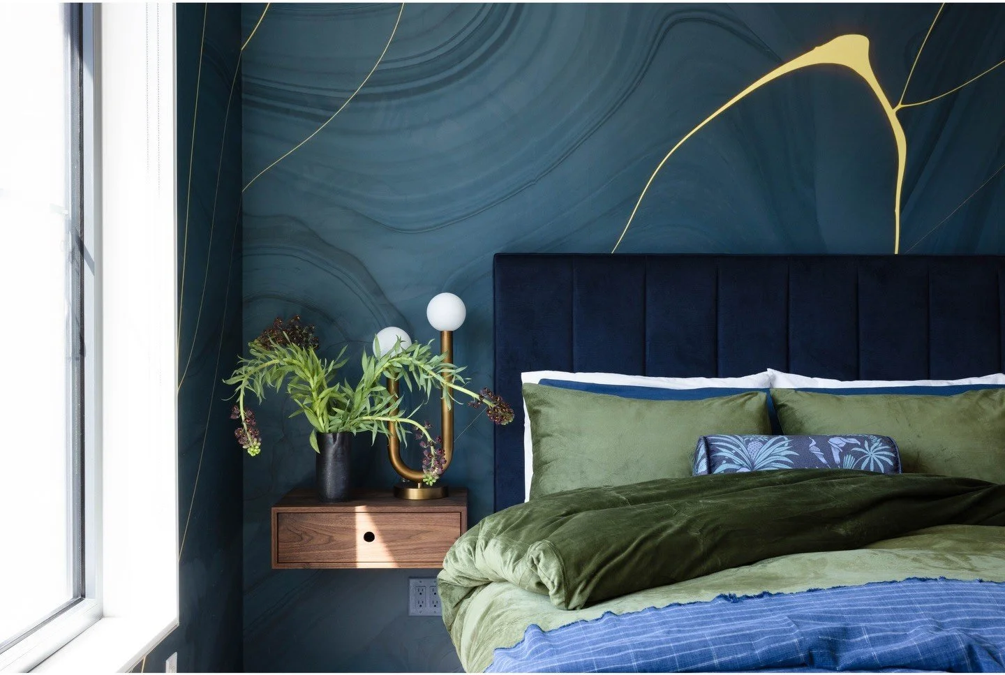 Blue bedroom with green bedding and an arched brass reading lamp