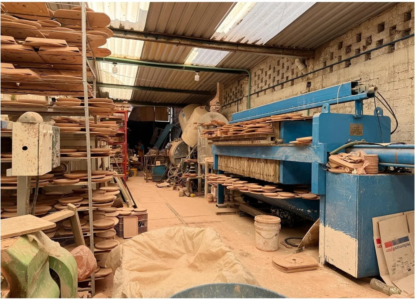 Ceramic production area with blue shelving and stacked clay pieces