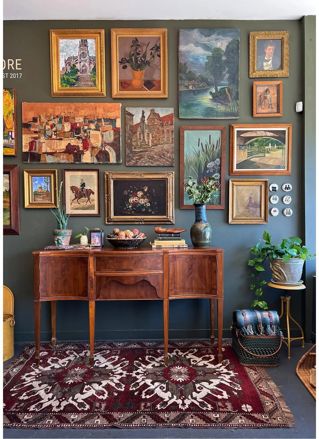 Dense gallery wall above a wood table and patterned rug