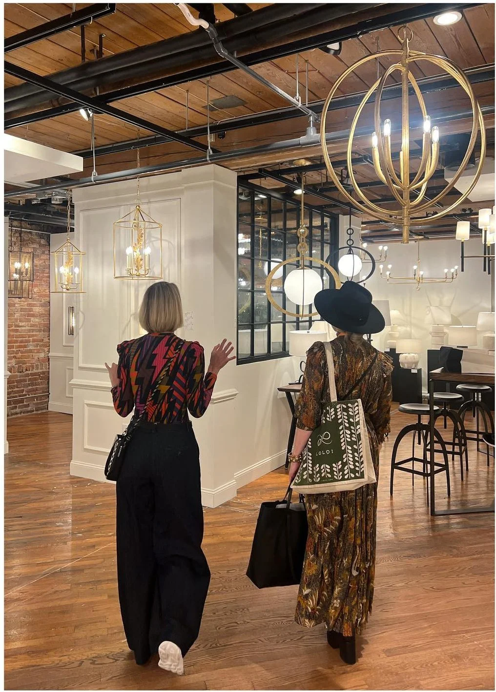 Designers walking through a showroom of brass and sculptural pendants