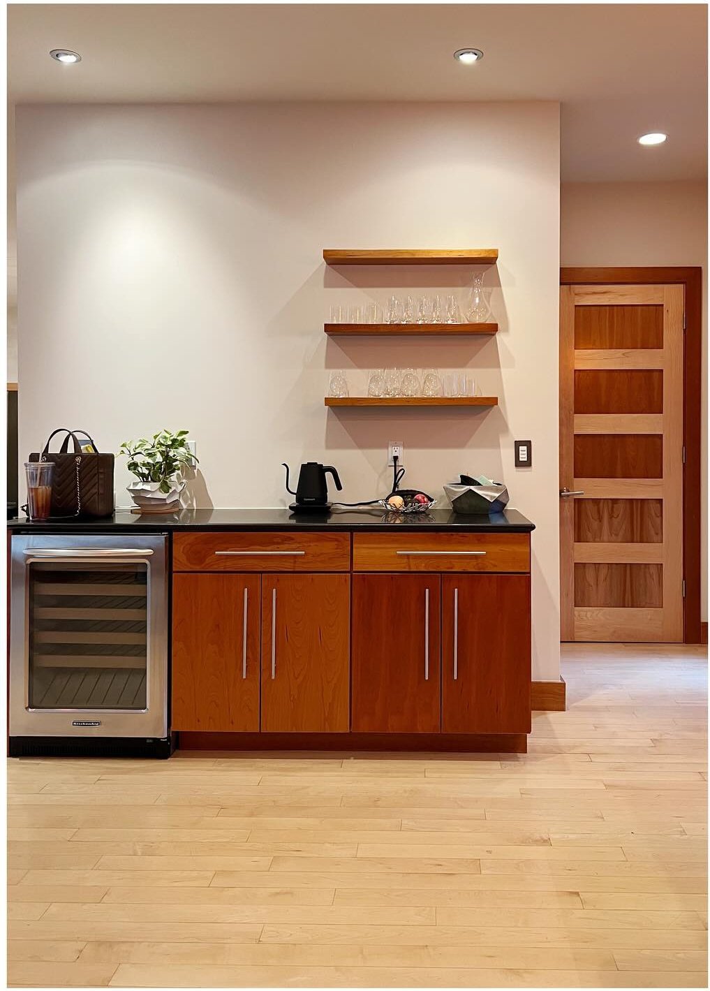 Original wood cabinets and wine refrigerator beside tall open shelving