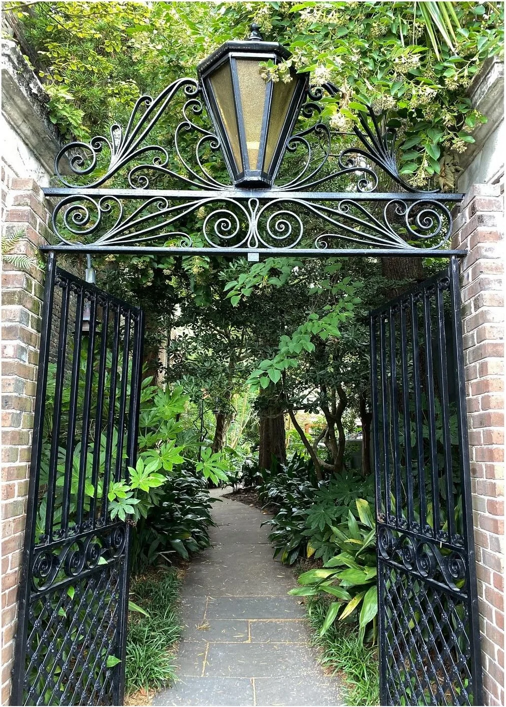 Ornate iron garden gate beneath climbing greenery