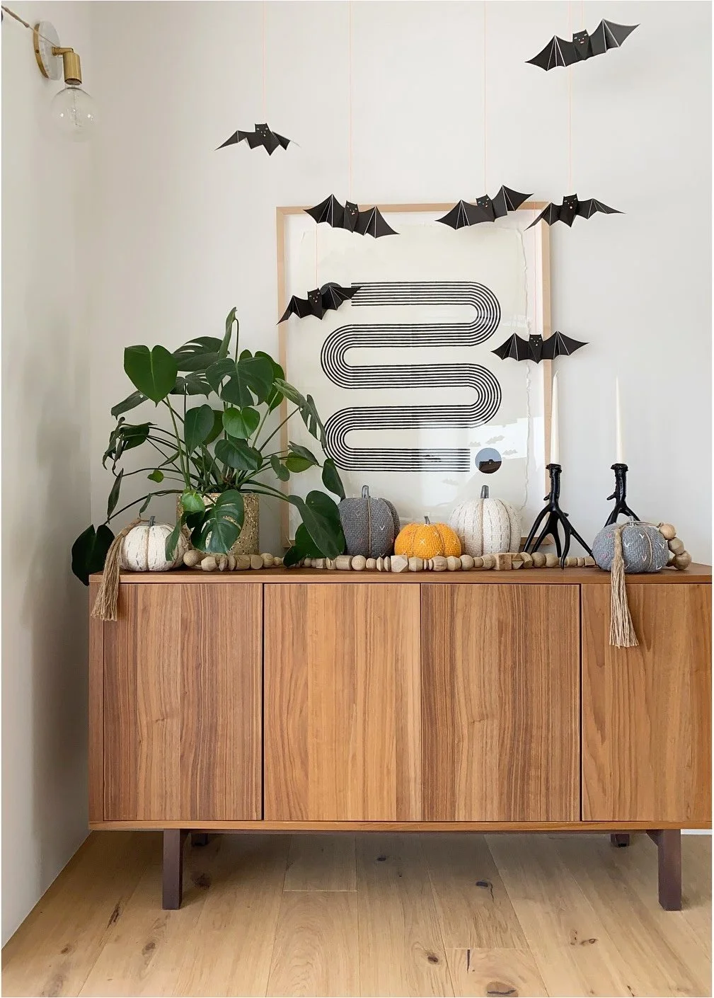 Wood sideboard with pumpkins black paper bats and a potted plant