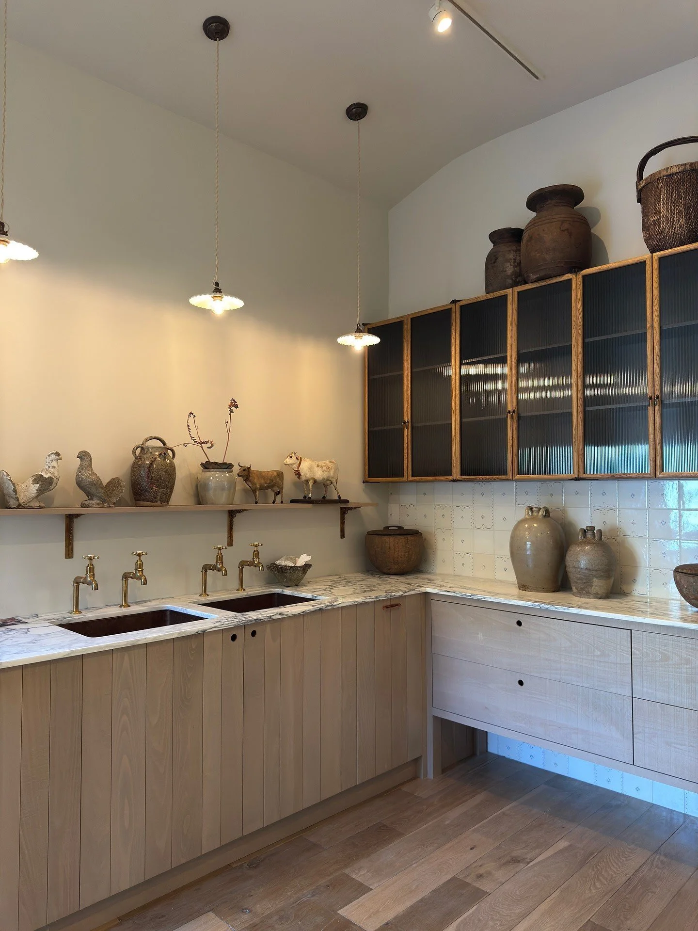 Pale kitchen cupboards and sink beneath dark glazed wall cabinets