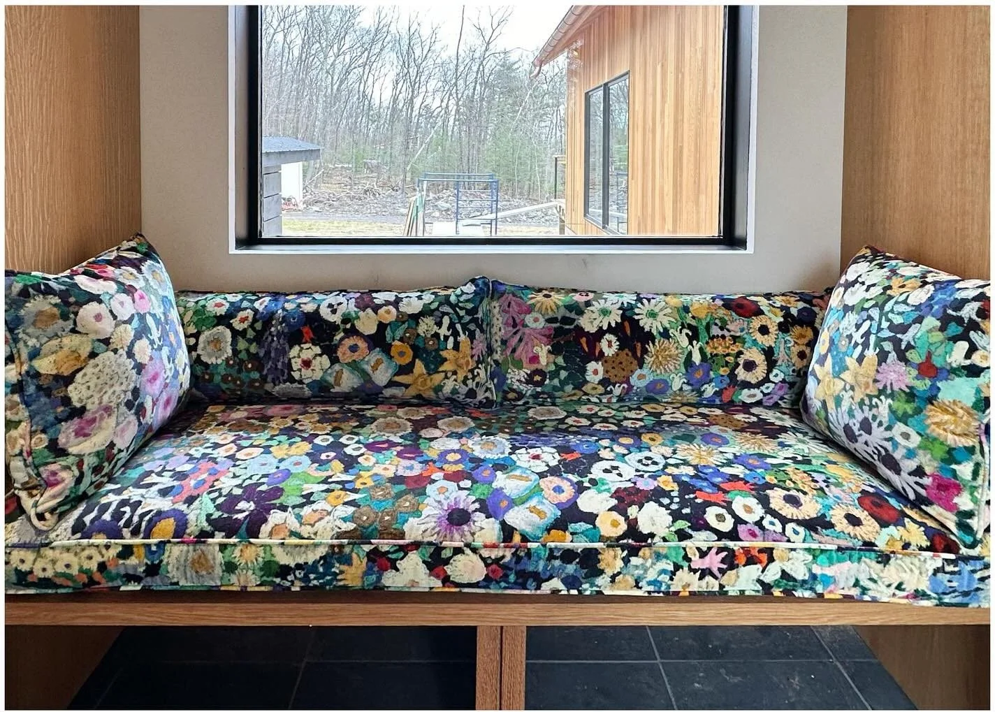 Floral upholstered window bench between pale wood cupboards