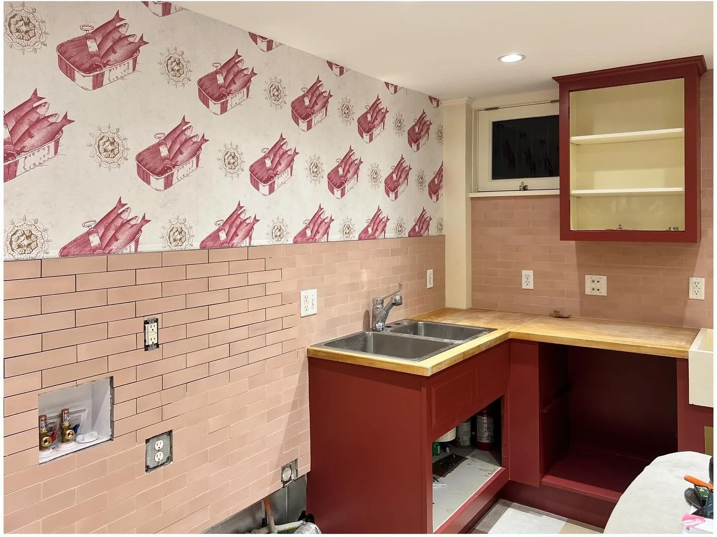 Renovation progress showing burgundy cabinets tile and patterned wallpaper