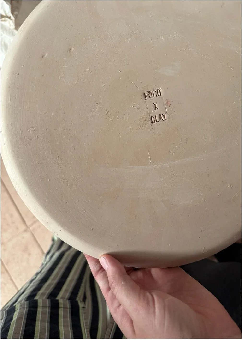 Hand holding the underside of an unfinished ceramic bowl