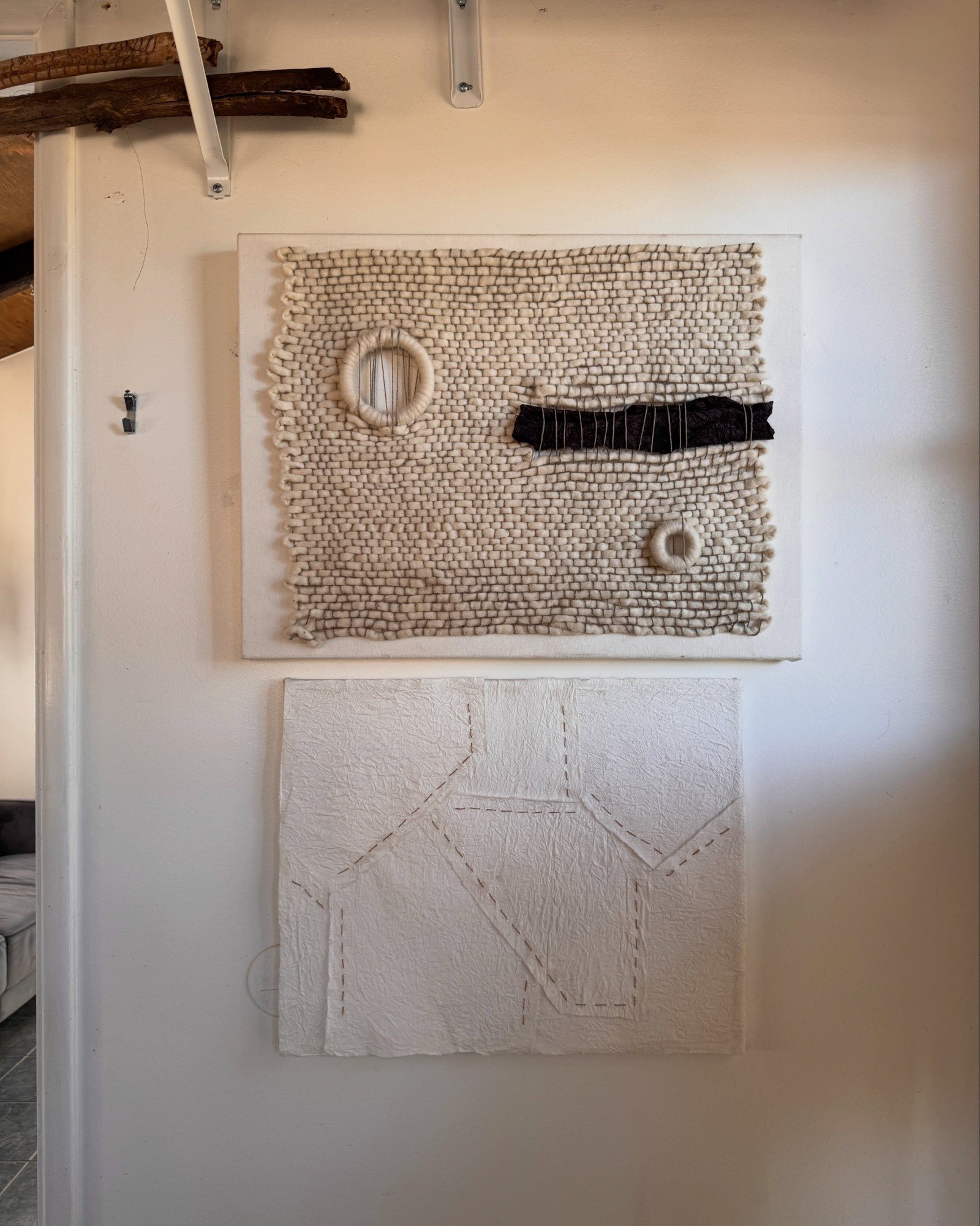 Textured monochrome fiber artwork on a white wall