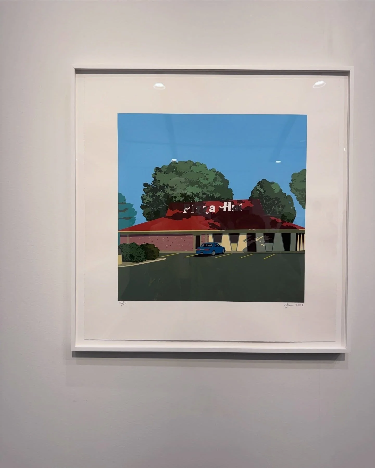 Framed landscape painting with a red building and green trees