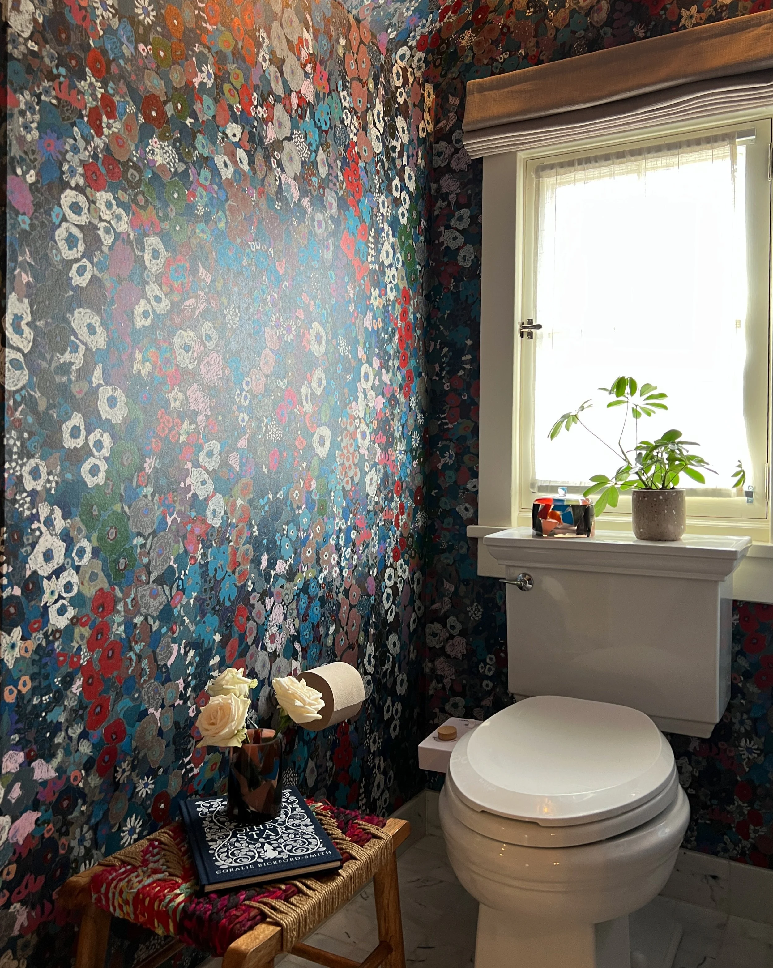 Powder room with dark floral wallpaper, a white toilet, and a window.